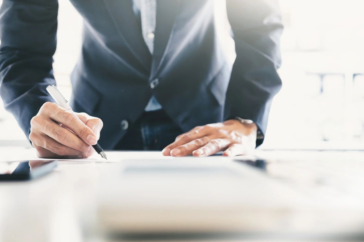 A man in a suit is writing on paper