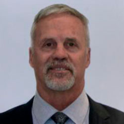 A man in suit and tie standing next to wall.