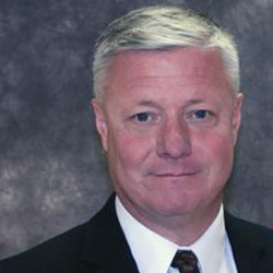 A man in suit and tie with white hair.